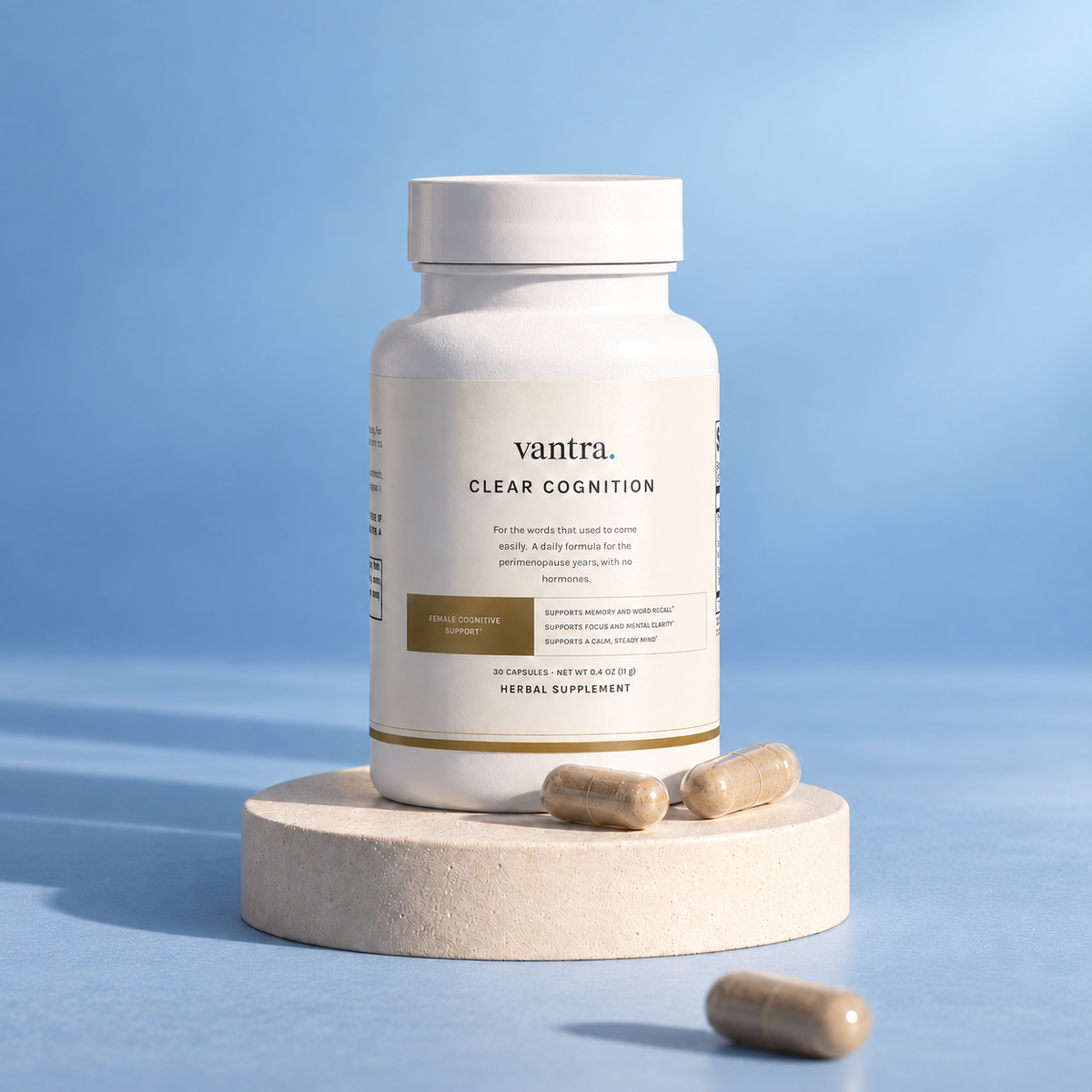Clear Cognition by Vantra, a white supplement bottle on a cream plinth with capsules, in soft light against a steel blue backdrop
