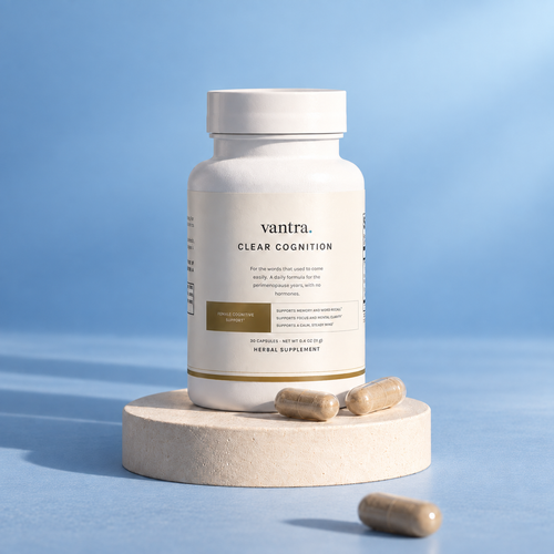 Clear Cognition by Vantra, a white supplement bottle on a cream plinth with capsules, in soft light against a steel blue backdrop